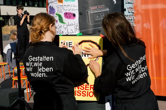 Zwei Menschen kleben ein selbstgebasteltes Plakat